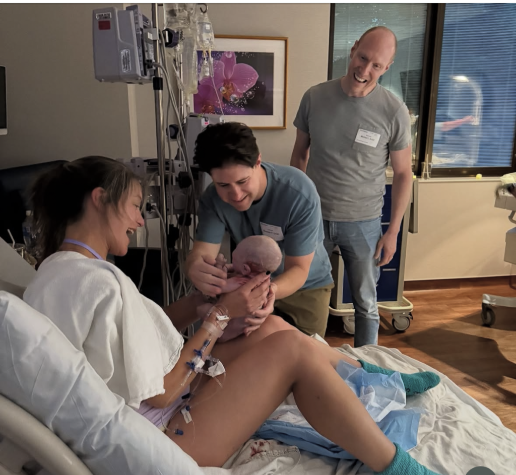 Surrogate handing baby to new parents.